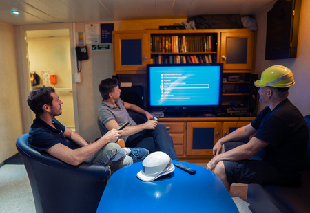 Happy team of ship officers watch TV onboard of vesselの写真素材