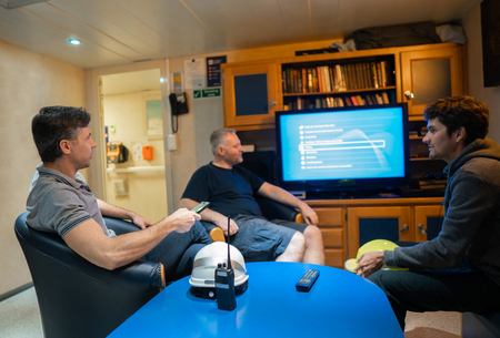 Happy team of ship officers watch TV onboard of vesselの写真素材