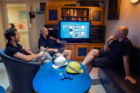 Happy team of ship officers watch TV onboard of vesselの写真素材