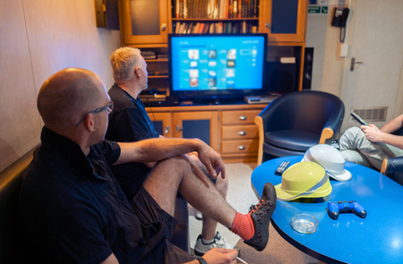 Happy team of ship officers watch TV onboard of vesselの写真素材