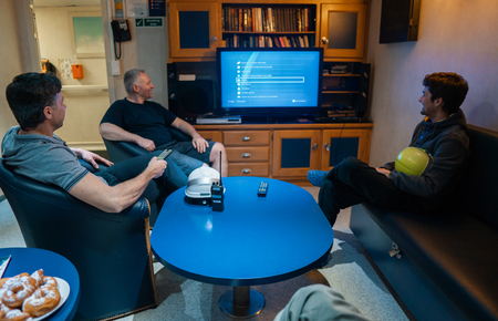 Happy team of ship officers watch TV onboard of vesselの写真素材