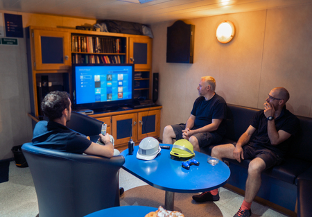 Happy team of ship officers watch TV onboard of vesselの写真素材