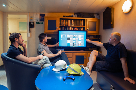 Happy team of ship officers watch TV onboard of vesselの写真素材