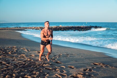 Tattooed bodybuilder sexy male coach at the beach.の写真素材