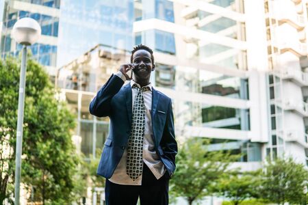 African American businessman holding mobile phone wearing blue suitの写真素材