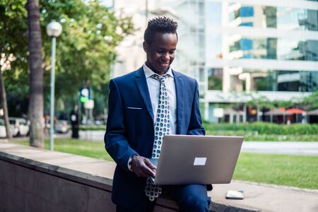 African American businessman holding laptop notebook wearing blue suitの写真素材