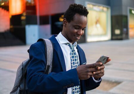 African American businessman holding mobile phone wearing blue suitの写真素材
