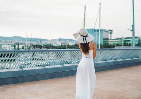 Pretty woman wearing white dress and pamela hat standingの写真素材