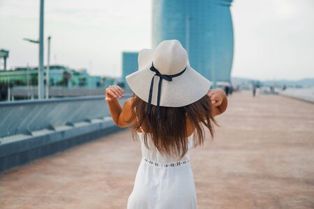 Pretty woman wearing white dress and pamela hat standingの写真素材