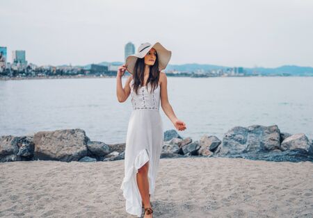 Pretty woman wearing white dress and pamela hat standingの写真素材