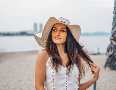 Pretty woman wearing white dress and pamela hat standingの写真素材