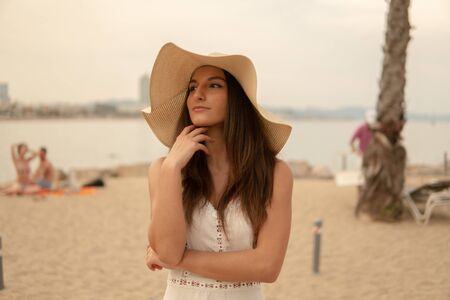 Pretty woman wearing white dress and pamela hat standingの写真素材