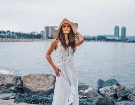 Pretty woman wearing white dress and pamela hat standingの写真素材