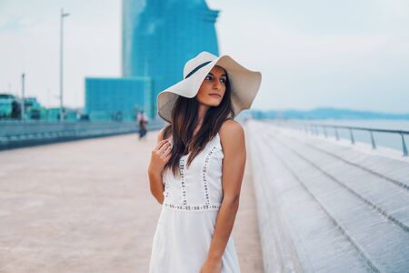 Pretty woman wearing white dress and pamela hat standingの写真素材