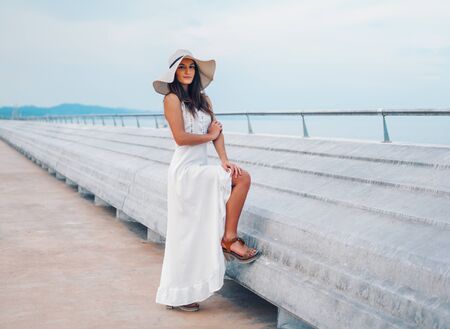 Pretty woman wearing white dress and pamela hat standingの写真素材