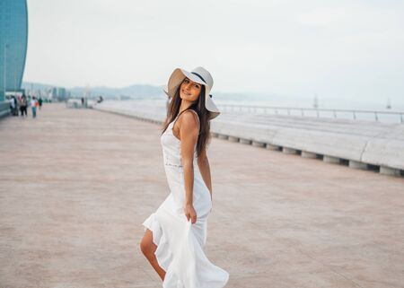 Pretty woman wearing white dress and pamela hat standingの写真素材