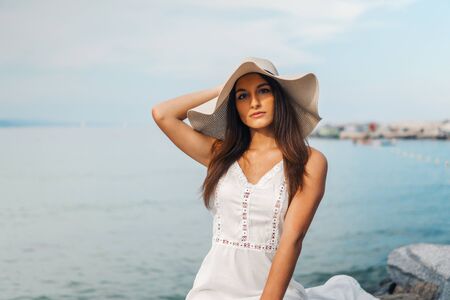Pretty woman wearing white dress and pamela hat standingの写真素材