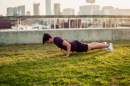 Young athletic man doing pushups exercises at parkの写真素材