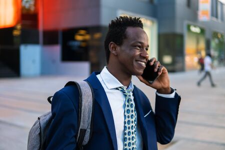 African American businessman holding mobile phone wearing blue suitの写真素材