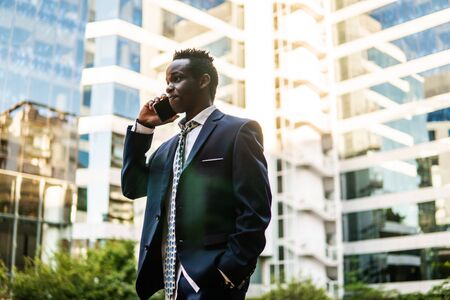 African American businessman holding mobile phone wearing blue suitの写真素材