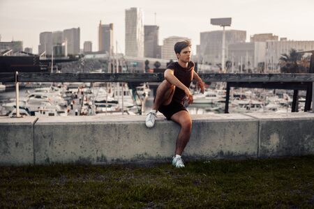 Young athletic man after running at park with skyscrapers backgroundの写真素材