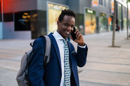 African American businessman holding mobile phone wearing blue suitの写真素材