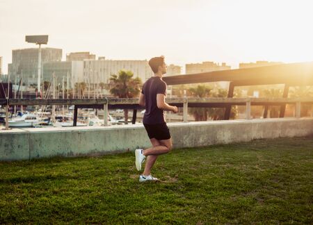 Young athletic man running at park with skyscrapers backgroundの写真素材