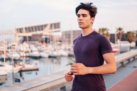 Young athletic man running at park during skyscrapers backgroundの写真素材