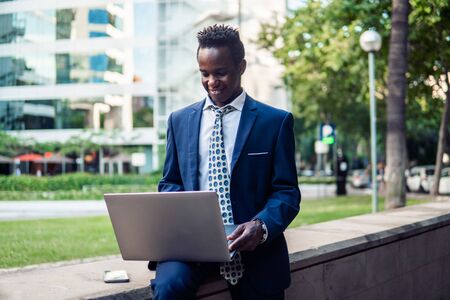 African American businessman holding laptop notebook wearing blue suitの写真素材