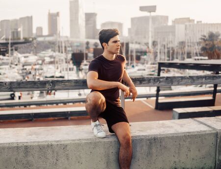 Young athletic man after running at park with skyscrapers backgroundの写真素材