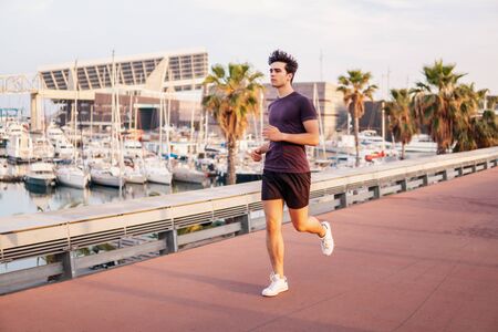 Young athletic man running at park during skyscrapers backgroundの写真素材