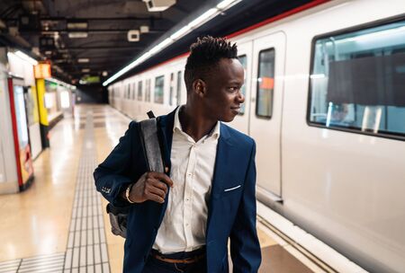 African American businessman wearing blue suit and backpackの写真素材