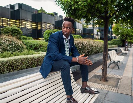 African American businessman wearing blue suit sits on the bench.の写真素材