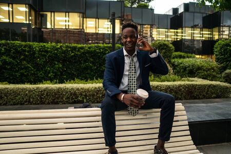 African American businessman holding mobile phone wearing blue suitの写真素材