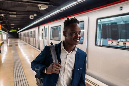 African American businessman wearing blue suit and backpackの写真素材