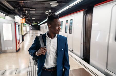 African American businessman wearing blue suit and backpackの写真素材