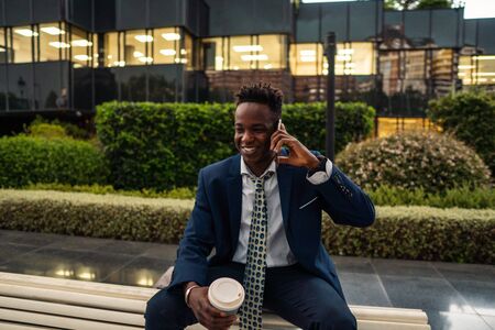 African American businessman holding mobile phone wearing blue suitの写真素材