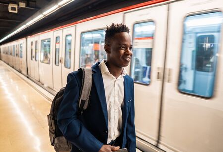African American businessman wearing blue suit and backpackの写真素材