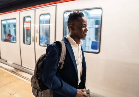 African American businessman wearing blue suit and backpackの写真素材