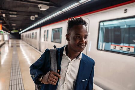 African American businessman wearing blue suit and backpackの写真素材