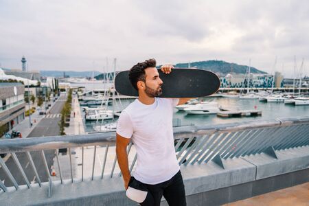 Skateboarder stands with skateboard in the modern city terraceの写真素材