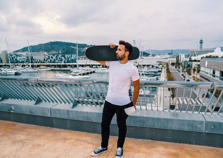 Skateboarder stands with skateboard in the modern city terraceの写真素材