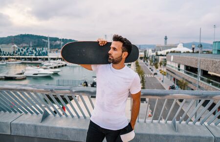 Skateboarder stands with skateboard in the modern city terraceの写真素材