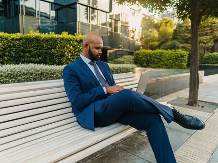 Indian businessman holding laptop notebook wearing blue suit near officeの写真素材