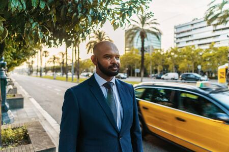 Indian businessman wearing blue suit standing near office or hotel.の写真素材