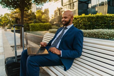 Indian businessman holding laptop notebook wearing blue suit near officeの写真素材
