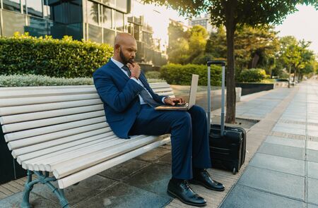 Indian businessman holding laptop notebook wearing blue suit near officeの写真素材