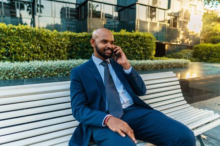 Indian businessman holding mobile phone wearing blue suitの写真素材