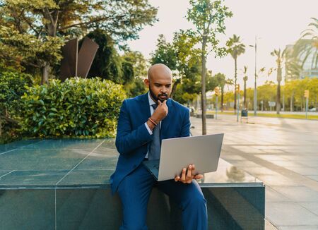 Indian businessman holding laptop notebook wearing blue suit near officeの写真素材