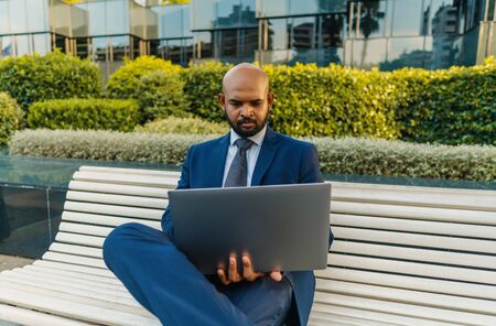 Indian businessman holding laptop notebook wearing blue suit near officeの写真素材